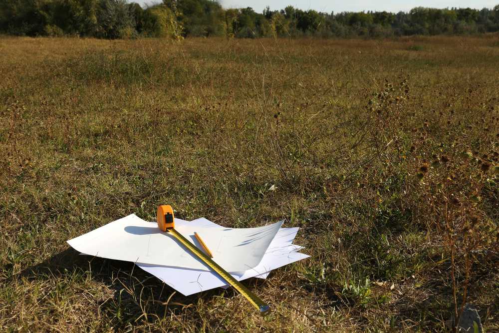 Maßband mit Unterlagen auf einem Baugrundstück